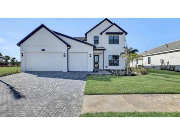 Two-story house with white exterior, gray driveway, and landscaping at 2625 Waterfront Cir, Sarasota, FL 34240