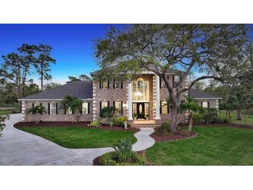 Stunning two-story brick home featuring a manicured lawn, elegant columns, and a grand entrance at 6722 Oakmont Way, Lakewood Ranch, FL 34202