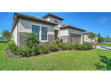 Beautiful one-story home featuring stone accents, a two-car garage, and a well-maintained lawn and landscaping at 429 Alberata Way, Nokomis, FL 34275