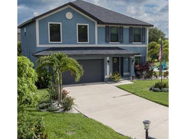 Charming two-story blue home with a gray roof, landscaped yard, and a concrete driveway at 8825 52Nd E Ave, Palmetto, FL 34221