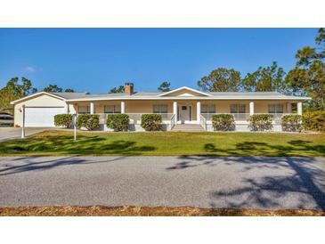 Charming single-story home featuring a columned front porch and a well-manicured lawn at 3125 Pickett St, Port Charlotte, FL 33981
