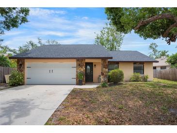 Charming single Gathering home featuring a white garage door, stone accents, and a well-maintained yard at 4175 Arrow Ln, Sarasota, FL 34232