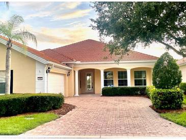 Lovely single-story home boasts a tile roof, brick driveway, covered front porch, and mature, manicured landscaping at 5901 Mariposa Ln, Sarasota, FL 34238