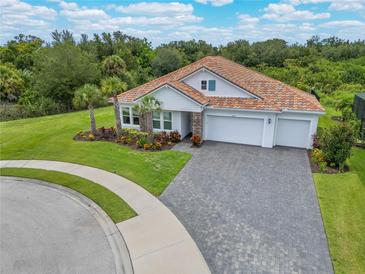 Home's exterior with a three-car garage and well-manicured lawn at 6600 Dovekey Dr, Sarasota, FL 34241