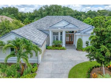 Elegant single-story home with a tile roof, white exterior, and lush landscaping at 6935 Cumberland Ter, University Park, FL 34201