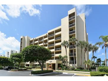 Tan multi-story condominium building with lush landscaping and parking at 1045 Gulf Of Mexico Dr # 403, Longboat Key, FL 34228