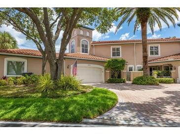 Tan three-story townhome with a white garage door and landscaped front yard at 1711 Starling Dr # 1711, Sarasota, FL 34231