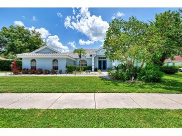 Beautiful light blue home with lush landscaping and a manicured lawn at 9044 Misty Creek Dr, Sarasota, FL 34241