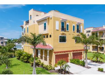 Beautiful yellow three-story home with a red roof, arched windows, palm trees and an attached two car garage at 1450 Silvia Shores Dr, Apollo Beach, FL 33572