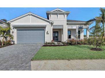 Two-story home with gray garage door, paved driveway, and landscaped lawn at 17931 Palmiste Dr, Bradenton, FL 34202