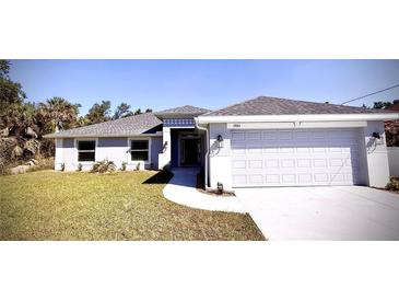 Beautiful one-story home showcasing a well-manicured lawn, a two-car garage, and a welcoming walkway to the front door at 3884 S Haberland Blvd, North Port, FL 34288