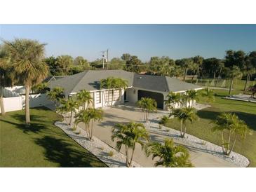 Aerial view of a single-story home with a large driveway and lush landscaping at 18770 Mcgrath Cir, Port Charlotte, FL 33948