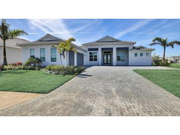 Beautiful single-story home with a well-manicured lawn, palm trees, and a large brick driveway at 17938 Palmiste Dr, Bradenton, FL 34202