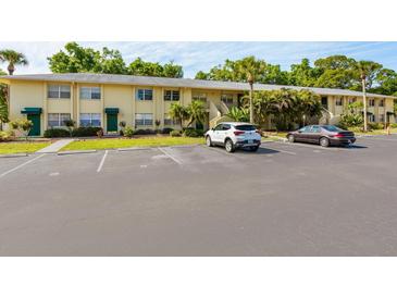 Exterior view of a light yellow condominium building with parking at 4805 Rilma Ave # 104, Sarasota, FL 34234