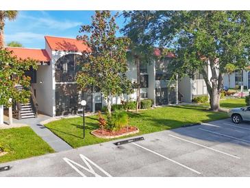 Condo building exterior showcasing a tiled roof, screened patios, and ample parking at 3245 Beneva Rd # 104, Sarasota, FL 34232