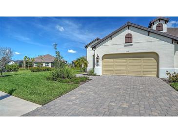 Well-maintained home with a tan garage door, manicured landscaping, and a brick paved driveway at 109 Corserra Dr, Nokomis, FL 34275