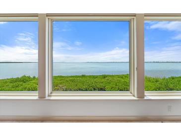 Stunning water view with lush greenery, visible through large windows, fills this light-filled room at 24 Tidy Island Blvd # 24, Bradenton, FL 34210