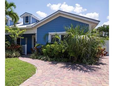 Charming blue house with brick paver driveway and lush landscaping at 213 75Th St, Holmes Beach, FL 34217
