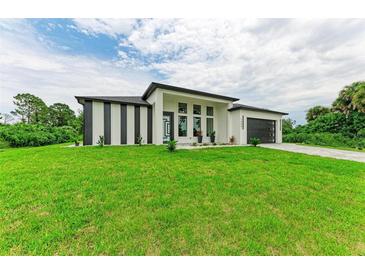 Modern house with a gray garage door and green lawn at 13457 Drysdale Ave, Port Charlotte, FL 33981
