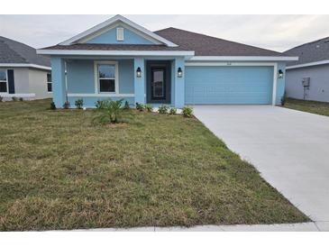 Charming single-story home showcases a blue exterior, manicured lawn, and a two-car garage at 2616 Averland Loop, North Port, FL 34287