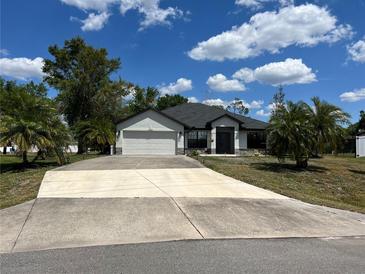 Charming single-story home featuring a wide driveway, attached garage, and lush tropical landscaping under a bright blue sky at 2204 Chipley Ave, North Port, FL 34286
