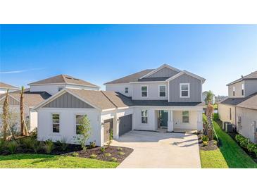 Two-story home showcases a white exterior, gray accents, well-manicured lawn, and an attached two-car garage at 9478 Tequila Sunrise Dr, Sarasota, FL 34241