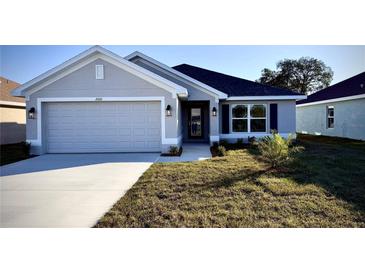 Modern two-car garage home with gray exterior and landscaped lawn at 2620 Averland Loop, North Port, FL 34287