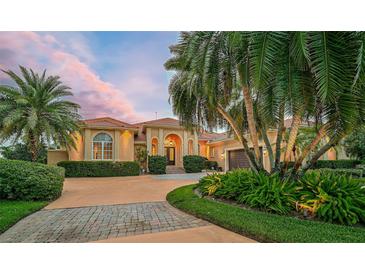 Elegant home featuring lush landscaping, a terracotta roof, and a circular driveway at 909 Macewen Dr, Osprey, FL 34229