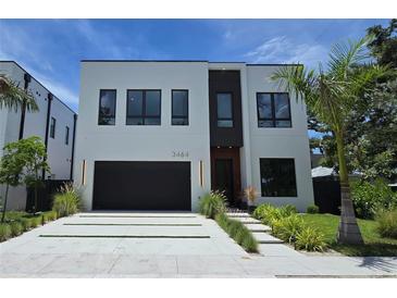 Modern two-story home with a black garage door, clean lines, and well-manicured landscaping at 3464 Camino Real, Sarasota, FL 34239