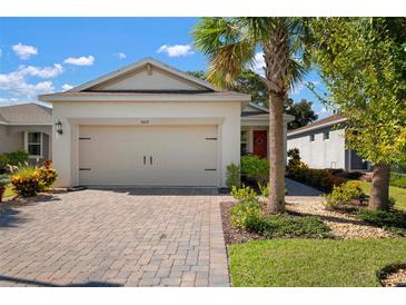 Single-story home with a beige garage door, paved driveway and nicely landscaped yard at 5619 Los Robles Ct, Palmetto, FL 34221