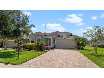 One-story home with light teal exterior, paver driveway, and landscaping at 11914 Brookside Dr, Bradenton, FL 34211