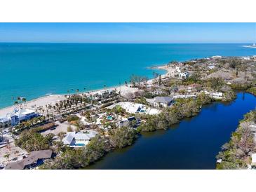 An aerial view showcases the waterfront homes along a picturesque sandy beach at 7665 Sanderling Rd, Sarasota, FL 34242