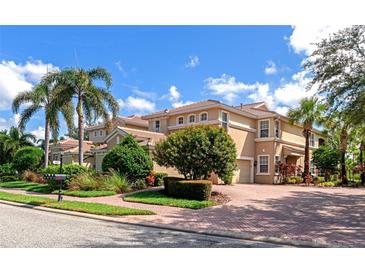 Beautiful tan two-story home with palm trees and landscaped yard at 943 River Basin Ct # 102B, Bradenton, FL 34212