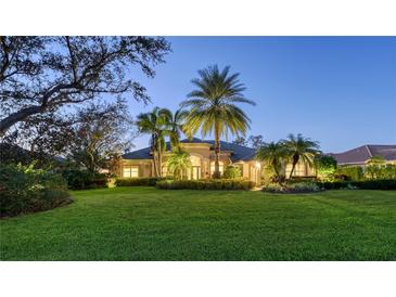 Well lit two story home with palm trees and lush landscaping at dusk at 2570 Tom Morris Dr, Sarasota, FL 34240