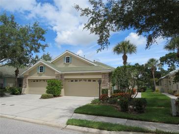 Tan two-car garage villa with lush landscaping at 4939 Lakescene Pl, Sarasota, FL 34243