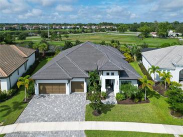 Beautiful aerial view of home featuring a three car garage, large lawn, manicured landscaping, and a paver driveway at 4629 Antrim Dr, Sarasota, FL 34240