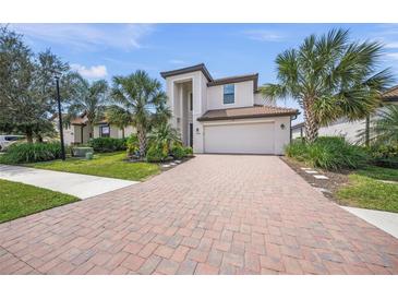 Two-story home with a well manicured front yard and a brick paver driveway leading to a two car garage at 19369 Nearpoint Dr, Venice, FL 34292