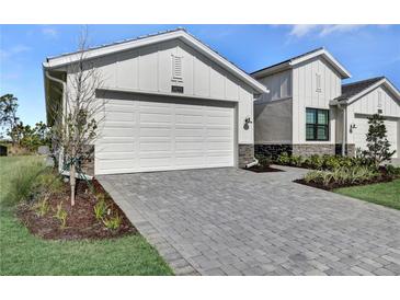Beautiful home featuring a spacious garage, manicured landscaping, and an inviting paver driveway at 18773 Dayspring Pl, Venice, FL 34293