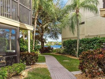 Brick-paved walkway through a lush, tropical backyard with water views at 6157 Midnight Pass Rd # A51, Sarasota, FL 34242