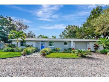 Gray brick ranch house with a blue door, landscaping, and gravel driveway at 2244 Palm Ter, Sarasota, FL 34231