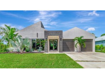 Contemporary home featuring unique architectural design, stone accents, lush landscaping, and an attached two-car garage at 8175 Dittmar St, Port Charlotte, FL 33981
