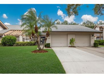 Two-car garage and front entry of condo with palm trees at 4573 Kingsmere # 27, Sarasota, FL 34235
