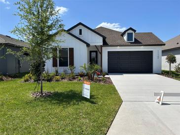 Charming home with modern farmhouse design, dark trim, manicured lawn and landscaping, and a concrete driveway at 11709 Capstan Pl, Parrish, FL 34219