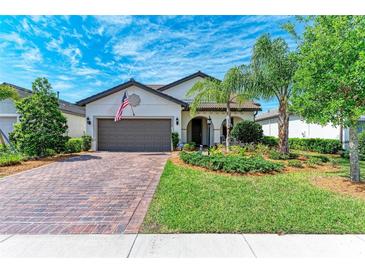 Charming single-Gathering home featuring a well-manicured lawn, brick driveway, and a two-car garage at 7572 Viola Loop, Lakewood Ranch, FL 34202