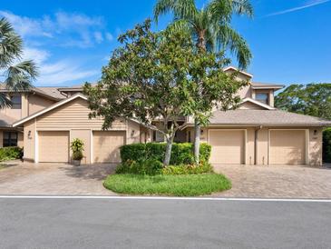 Tan colored townhouses with attached garages and landscaping at 5283 Heron Way # 204, Sarasota, FL 34231