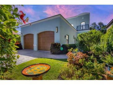 Charming two-story home with a two-car garage, mature landscaping, and a decorative bird bath at 1884 Grove St, Sarasota, FL 34239