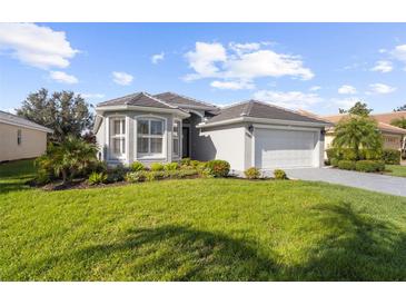 Single-story home with gray roof, white garage door, and manicured lawn at 5207 Pine Shadow Ln, North Port, FL 34287