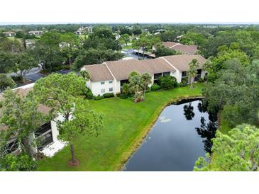 Aerial view of a condo community featuring lush landscaping and a tranquil pond at 752 White Pine Tree Rd # 206, Venice, FL 34285