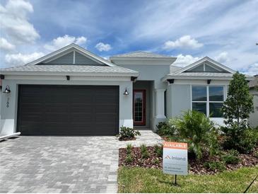Charming single-story home featuring a well-manicured lawn, brick driveway, and a two-car garage with a stylish red front door at 766 Hillshire Pl, Spring Hill, FL 34609