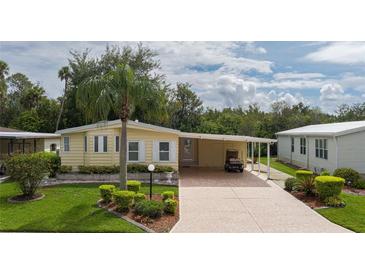 Yellow single-wide mobile home with carport and landscaping at 8454 Imperial Cir, Palmetto, FL 34221